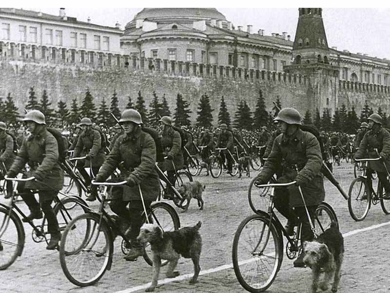 Военные собаководы РККА на велосипедах, одеты в армейские бушлаты (ватные куртки образца 1935 года), парад 1 мая 1938 года.