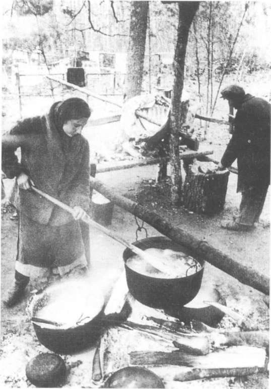 Партизаны из отряда «Котовский» при приготовлении пищи в лесном лагере в Белоруссии, декабрь 1943 г.