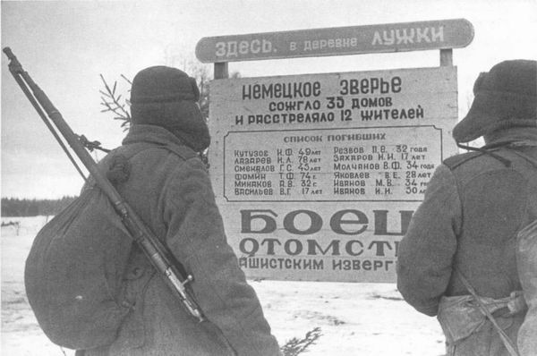Советские солдаты перед плакатом, сообщающим о зверствах врага, 1943 г.