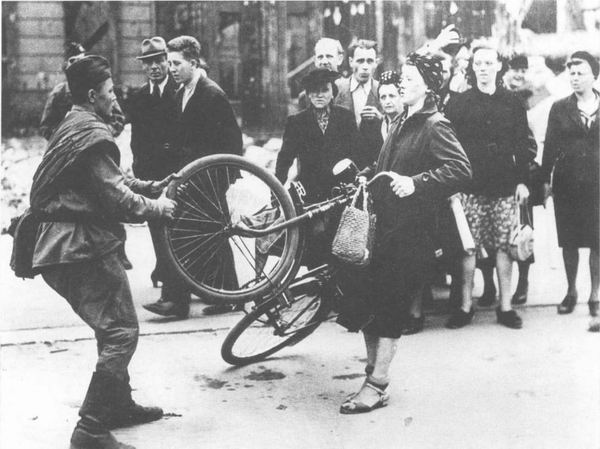 Советский солдат отнимает велосипед у жительницы Берлина, 1945 г.